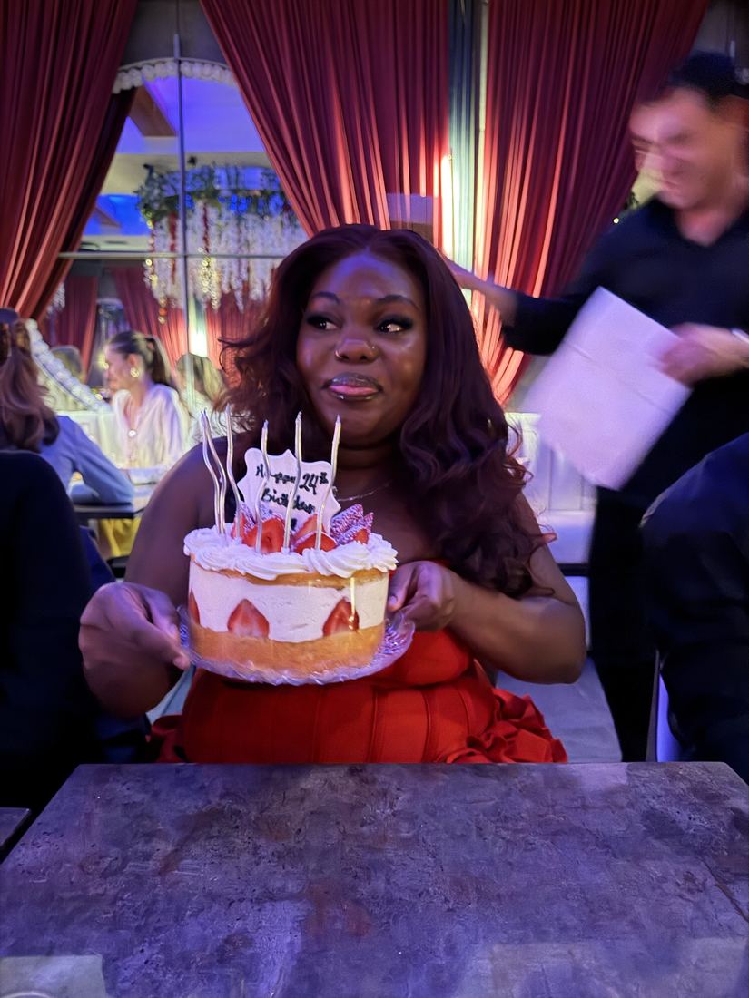 Gizelle holding her birthday cake with a playful face